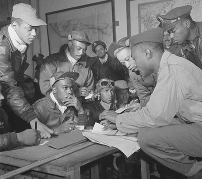 Tuskegee Airmen gather at Ramitelli, Italy, March 1945. Front row, left to right: unidentified airman; Jimmie D. Wheeler (with goggles); Emile G. Clifton (cloth cap).