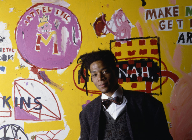 Jean-Michel Basquiat standing in front of one of his paintings.