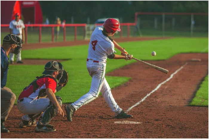 A batter takes a swing during a baseball game. Baseball incorporates several types of physical exertion, including throwing the ball, swinging the bat, and running in the outfield and around the bases.