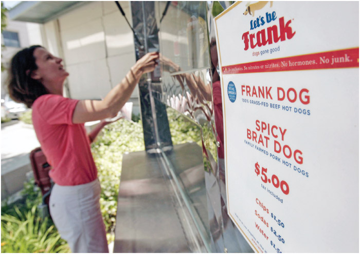A woman purchases a hot dog made from grass-fed animals.