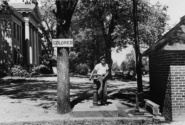 A young boy drinks from a water fountain marked for “colored” users on the county courthouse lawn in Halifax, North Carolina, in April 1938.