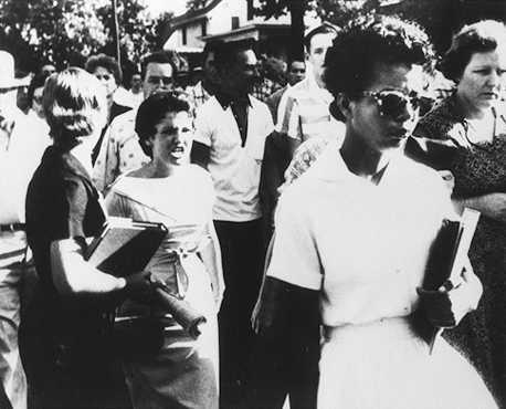 Elizabeth Echford walks to Little Rock High School with a crowd behin her in September 1957, shortly after the Supreme Court ruled in favor of desegregation. AP/Wide World Photos. Reproduced by permission.
