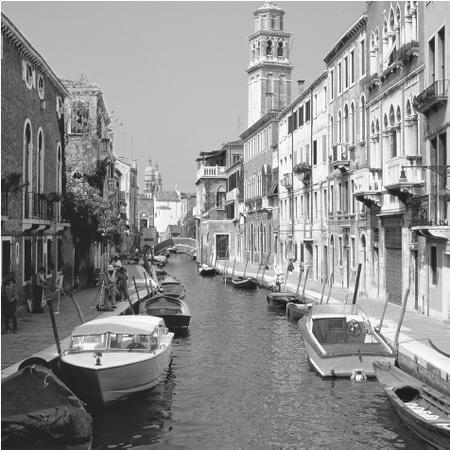 Boats float in a canal lined by houses in Venice.
