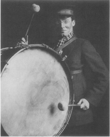 A Salvation Army volunteer bangs a drum in a production of Major Barbara