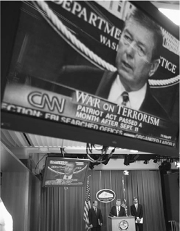 Attorney General John Ashcroft, center, is seen on video screens discussing the secret Foreign Intelligence Surveillance Courts wiretap ruling on November 18, 2002, in Washington, D.C. (APWide World Photos)