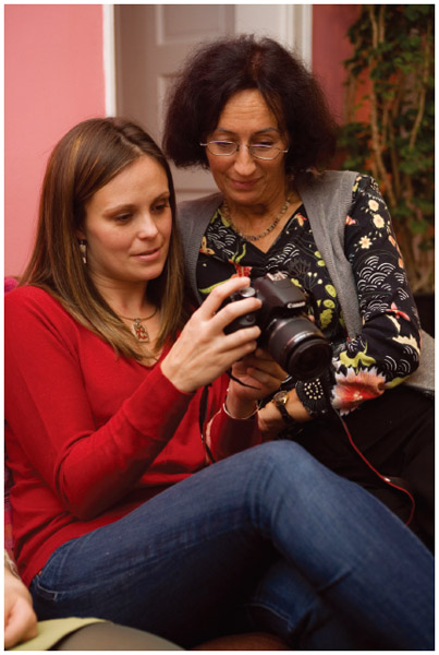 A woman shares photos stored on her digital camera with her aunt. Both emigrated from Poland to the U.S.