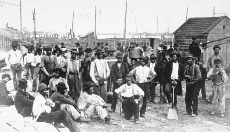 A group of African American men, former slaves freed by the Civil War and its aftermath, gather to look for work at a harbor.