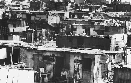 People sit in front of shacks in the slum village of Cross Roads, South Africa, 1978