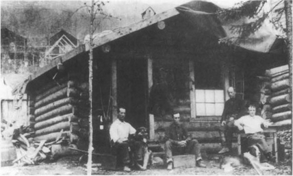 Marshall and Louis Bond with their dog, Jack, the inspiration for Buck in Jack Londons The Call of the Wild, sitting in front of a log cabin in the Yukon.