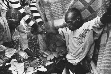 Some people with terminal diseases seek out alternative forms of medical help. Here, an HIV-positive man consults a traditional healer in Matibi, Zimbabwe. The man is inhaling herbal smoke to invoke his ancestral spirits to help cure him.