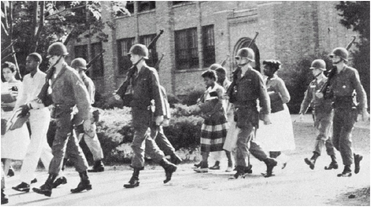 Federal troops escorting four black students to Little Rock Central High School to protect them from other students and protestors and ensure their entry into the school.