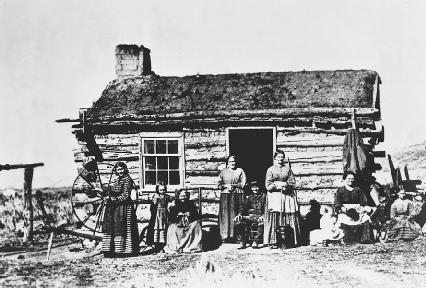 Mormon family assembled in front of a log cabin, spinning wheel to the left, in Utah, in 1875. Reproduced by permission of © Bettmann/Corbis.